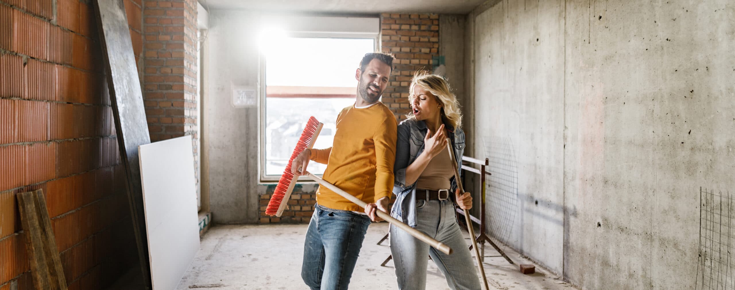 Full length of a young couple having fun while pretending to be musicians during their home renovation process. Copy space.