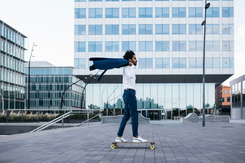 jeune homme faisant du skateboard devant un immeuble de bureau.